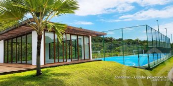 Academia envidraçada e quadra poliesportiva do Reserva Byom, rodeadas por áreas verdes no condomínio em Busca Vida.