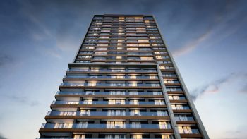 Fachada do Beach Class Bahia vista de baixo para cima, com varandas, linhas modernas e iluminação natural no Caminho das Árvores, Salvador.