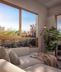 Sala de estar com sofá claro, janela ampla e jardineira com flores e vegetação externa.