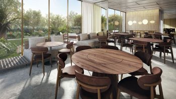 Salão de festas moderno com mesas redondas, cadeiras de madeira e amplas janelas com vista para o jardim.