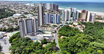 Vista aérea da implantação do TOM Colina de Patamares na Colina de Patamares, mostrando o empreendimento, a orla de Salvador, áreas verdes e o entorno do bairro.