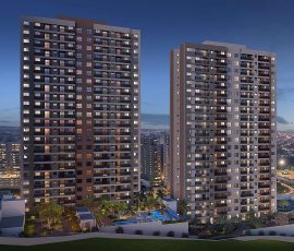 Fachada noturna das torres do Mood Sol Bahia com apartamentos iluminados, paisagismo e piscina na área de lazer.